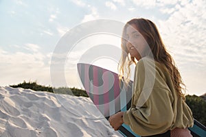 Portrait Of Young Woman Surfer At The Beach Walking Up Sand Dunes