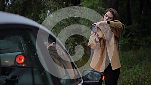 Portrait of young woman taking photos of damaged car for insurance after traffic accident. Caucasian female driver