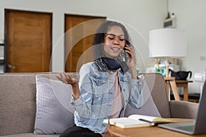 Portrait of young woman talk on smartphone write laptop in home office. Beautiful girl at desk computer take home order