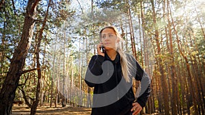 Portrait of young woman talking by phone in pine tree forest