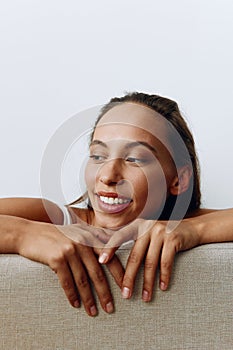 A portrait of a young woman with tanned skin and a beautiful smile with white teeth lies leaning on her hands. Beautiful