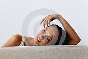 A portrait of a young woman with tanned skin and a beautiful smile with white teeth lies leaning on her hands. Beautiful