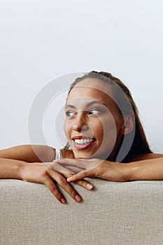 A portrait of a young woman with tanned skin and a beautiful smile with white teeth lies leaning on her hands. Beautiful