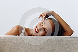 A portrait of a young woman with tanned skin and a beautiful smile with white teeth lies leaning on her hands. Beautiful