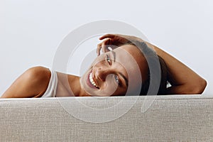 A portrait of a young woman with tanned skin and a beautiful smile with white teeth lies leaning on her hands. Beautiful