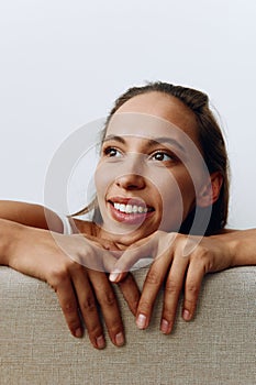 A portrait of a young woman with tanned skin and a beautiful smile with white teeth lies leaning on her hands. Beautiful