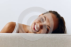 A portrait of a young woman with tanned skin and a beautiful smile with white teeth lies leaning on her hands. Beautiful