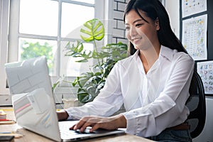 Portrait of young woman teacher with laptop at desk in classroom