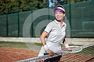Portrait of young woman in tennis court with racket. Beautiful female tennis player