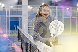 Portrait of a young woman tennis player standing with a padel racket