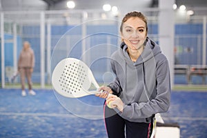 Portrait of a young woman tennis player standing with a padel racket