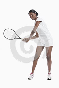 Portrait of young woman with tennis racket standing over white background