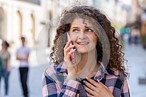 Happy woman girl having remote conversation talking on smartphone, good news gossip in city street