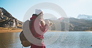 Portrait of young woman travel photographer making shot of epic mountain on lake
