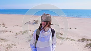 Portrait of young woman traveller with backpack on sea sand beach on vacation.