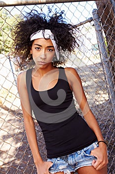 Portrait Of Young Woman In Urban Setting Standing By Fence