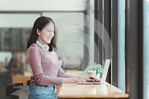 Portrait of young woman using laptop at cafe, business person working on laptop computer at a coffee shop