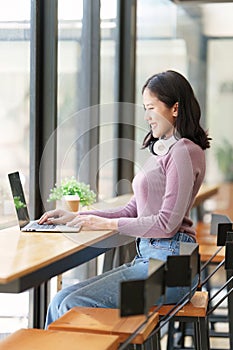 Portrait of young woman using laptop at cafe, business person working on laptop computer at a coffee shop