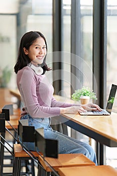 Portrait of young woman using laptop at cafe, business person working on laptop computer at a coffee shop