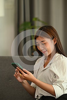 Portrait of a young woman using smart phone while sitting on couch.