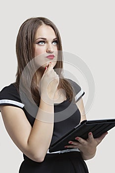 Portrait of young woman using tablet PC over gray background