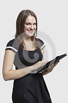 Portrait of young woman using tablet PC over gray background