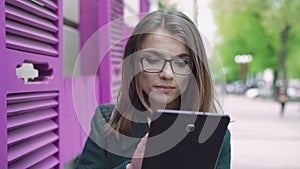 Portrait of young woman using a tablet on a street 4k