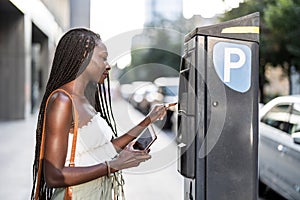 Young woman using using parking meter on a city street