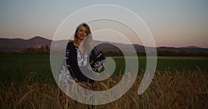 Portrait of young woman village girl national ukrainian shirt stands in a wheat field in sunset rays of light