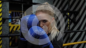 Portrait of a young woman wearing boxing gloves in a gym. Women's boxing.