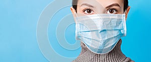 Portrait of young woman wearing medical mask at blue background. Protect your health. concept