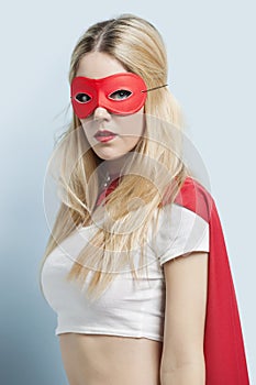 Portrait of young woman wearing superhero costume against blue background