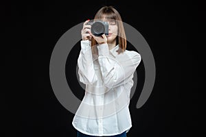 Portrait of a young woman wearing a white shirt holding a camera in her hand. The concept of a successful photographer