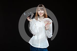 Portrait of a young woman wearing a white shirt, holding a camera and Russian rubles in her hand. The concept of a