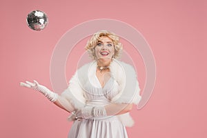 Portrait of young woman in white dress on coral pink background. Female model as a legendary actress. Pin up. Concept of