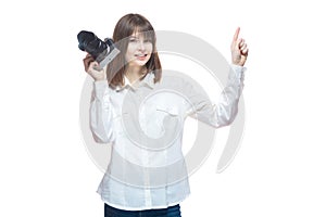 Portrait of a young woman in a white shirt, holding a camera in her hand and pointing her finger at the information. The