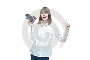 Portrait of a young woman in a white shirt, holding a camera in her hand and pointing her finger at the information. The