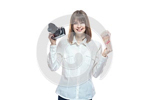 Portrait of a young woman in a white shirt holding a camera and Russian money rubles in her hand. The concept of a