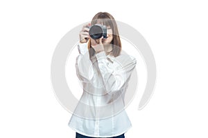 Portrait of a young woman in a white shirt taking pictures with a camera. The concept of a successful photographer