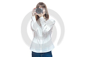 Portrait of a young woman in a white shirt taking pictures with a camera. The concept of a successful photographer