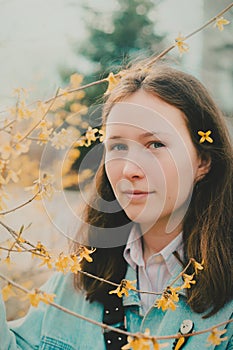 Portrait of an young woman who enjoys the scent of yellow flowers and early warm spring. Happiness and tenderness of spring days