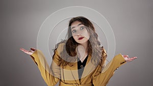 Portrait of young woman who is shrugging her shoulders on white background in slowmo