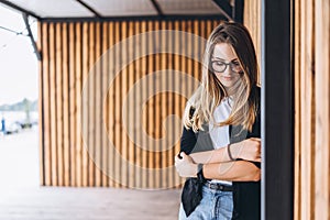 Portrait of a young woman on the wooden background with vertical boards. Beautiful girl with long hair and glasses smiling