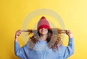 Portrait of a young woman with woolen hat on her eyes in a studio.