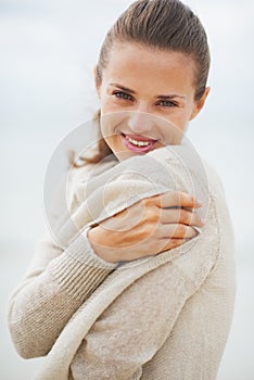 Portrait of young woman wrapping in sweater on coldly beach