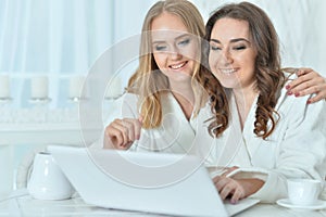 Portrait of young women in bathrobes with laptop