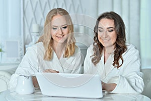 Portrait of young women in bathrobes with laptop