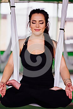 Portrait young women making antigravity yoga in the lotus position. Aerial aero fly fitness. white hammocks.