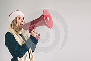 Portrait of young women shouting using megaphone over background Girl in white shirt, studio shot.