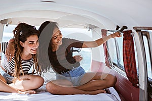 Portrait young women sitting inside of retro van look around